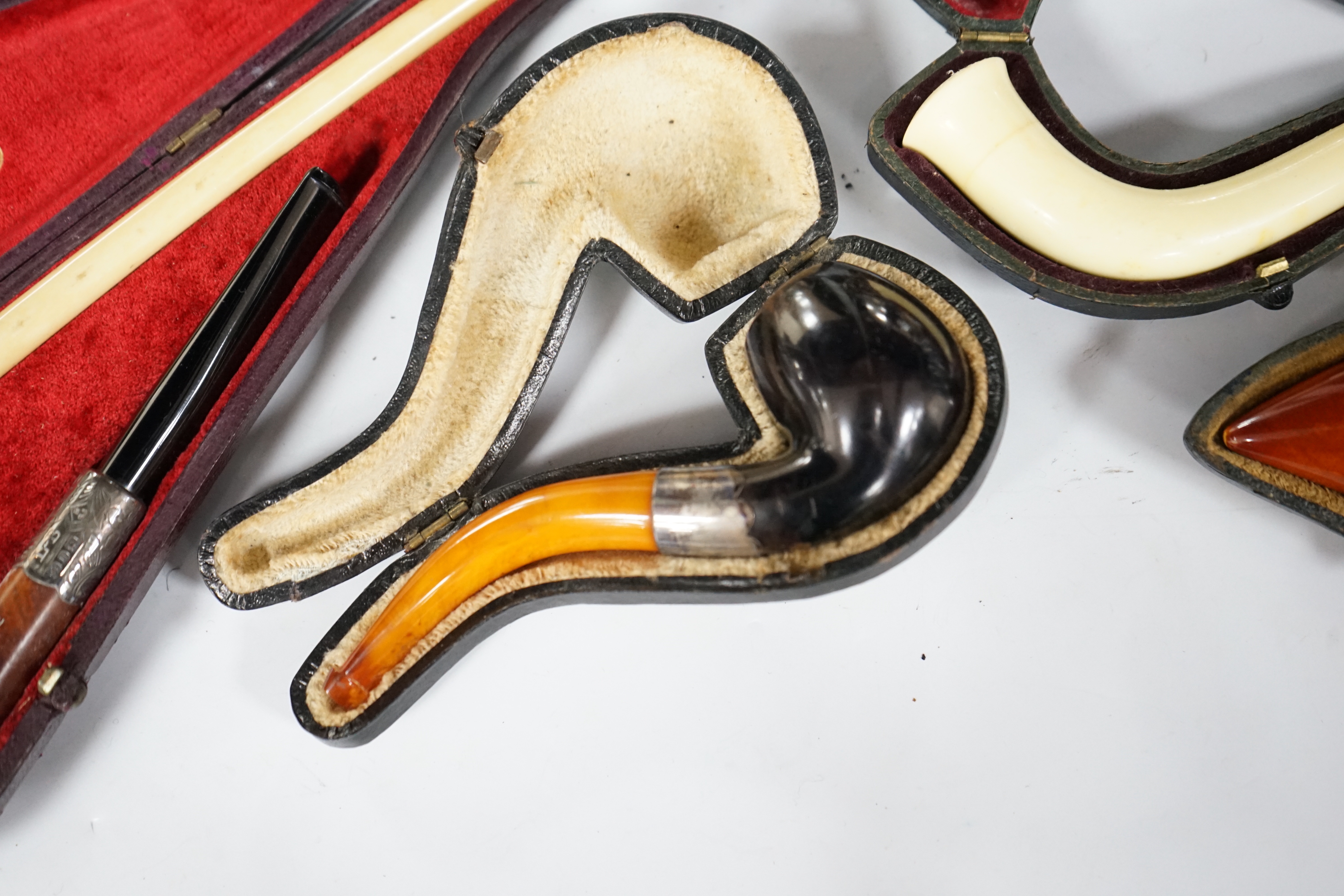 Seven cased pipes in varying sizes, some with amber mouthpieces, largest 19cm long